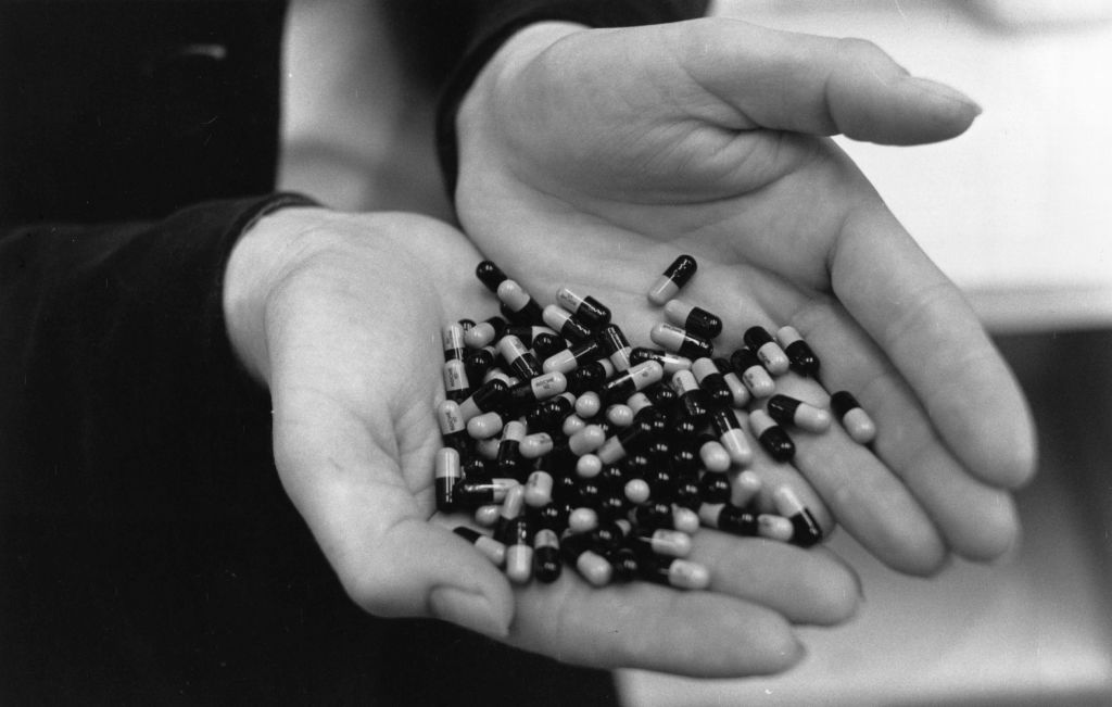 A close-up of hundreds of drug capsules held in a pair of hands