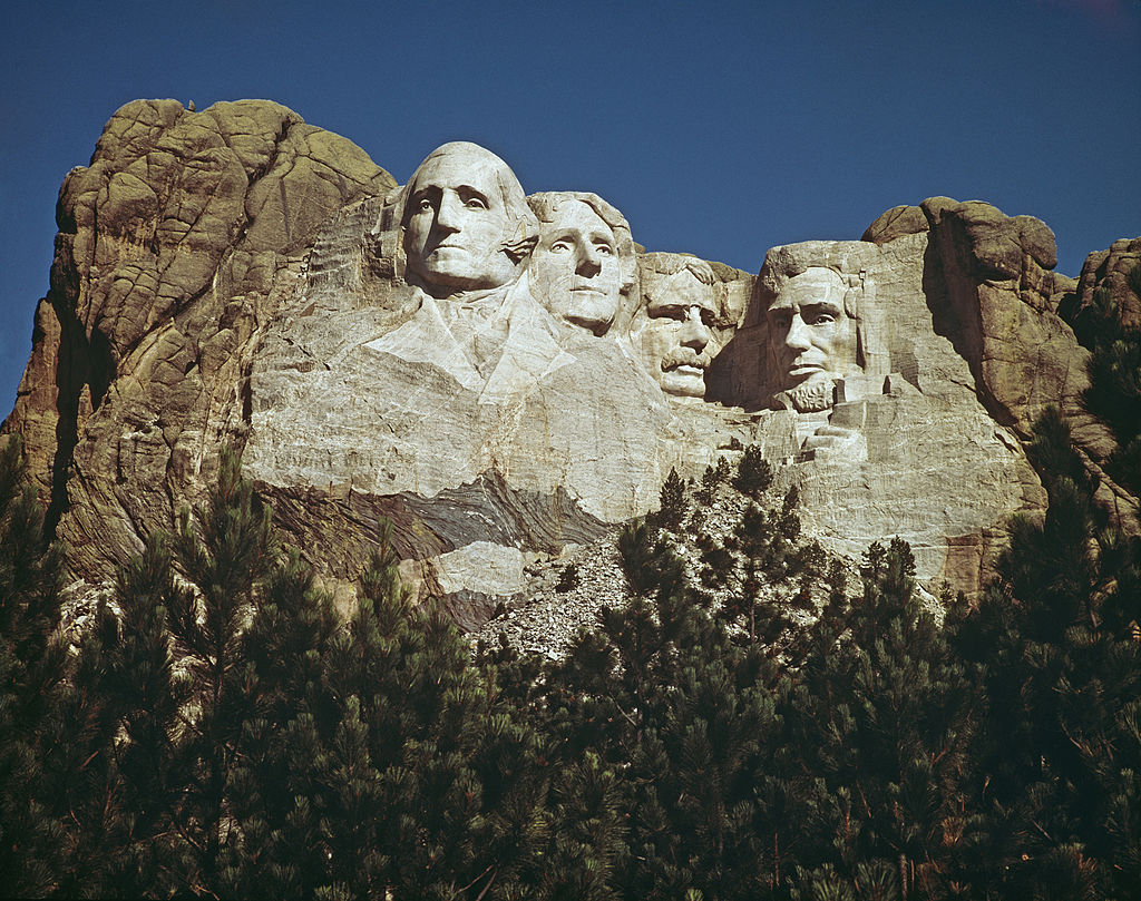 The Mount Rushmore National Memorial in South Dakota, USA, featuring the carved stone faces of US Presidents George Washington, Thomas Jefferson, Theodore Roosevelt and Abraham Lincoln, circa 1960.