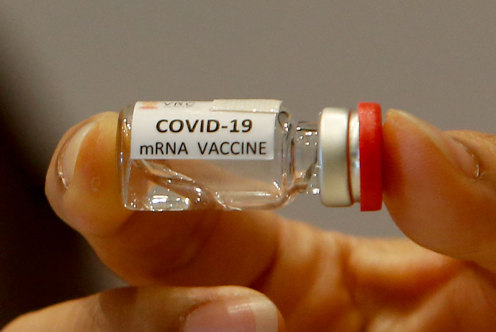 A researcher holds a COVID-19 mRNA vaccine during a news conference at the National Primate Research Center of Chulalongkorn University.