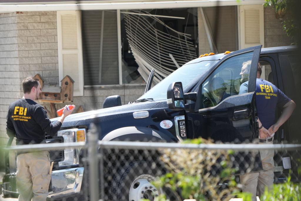 With a broken window in the background, FBI agents process the home of Craig Robertson who was shot and killed by the FBI in a raid on his home this morning on August 9, 2023 in Provo, Utah.