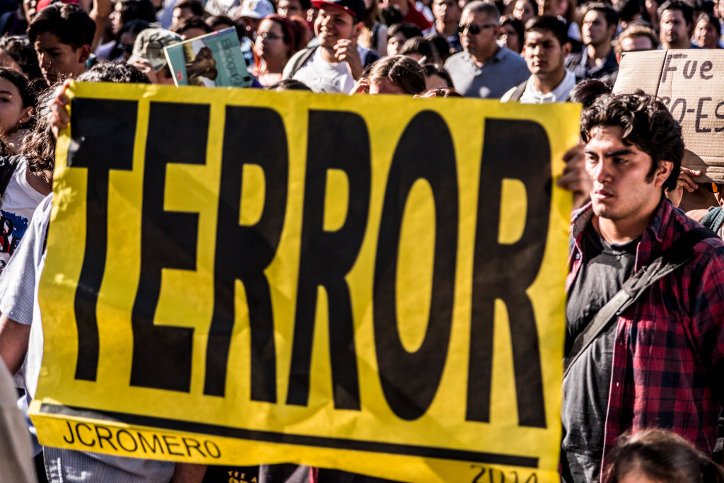 26 April 2018, Mexico, Guadalajara: Demonstrators carry a banner which reads 'Terror' during a protest march following the murder of three film students.