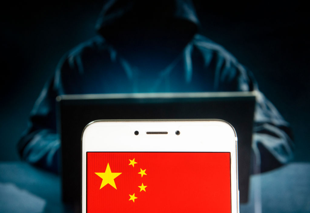 People's Republic of China flag is seen on an Android mobile device with a figure of hacker in the background.