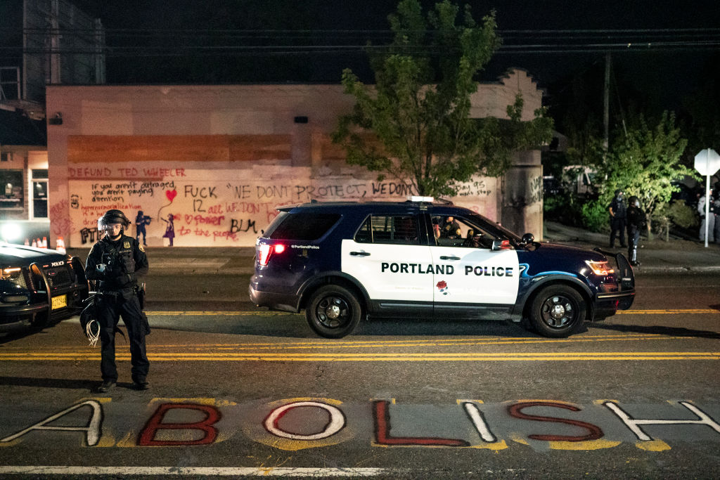 A Portland police officer looks down at graffiti calling for the abolition of cops after the crowd set fire to the Portland Police Association (PPA) building early in the morning on August 29, 2020 in Portland, Oregon.