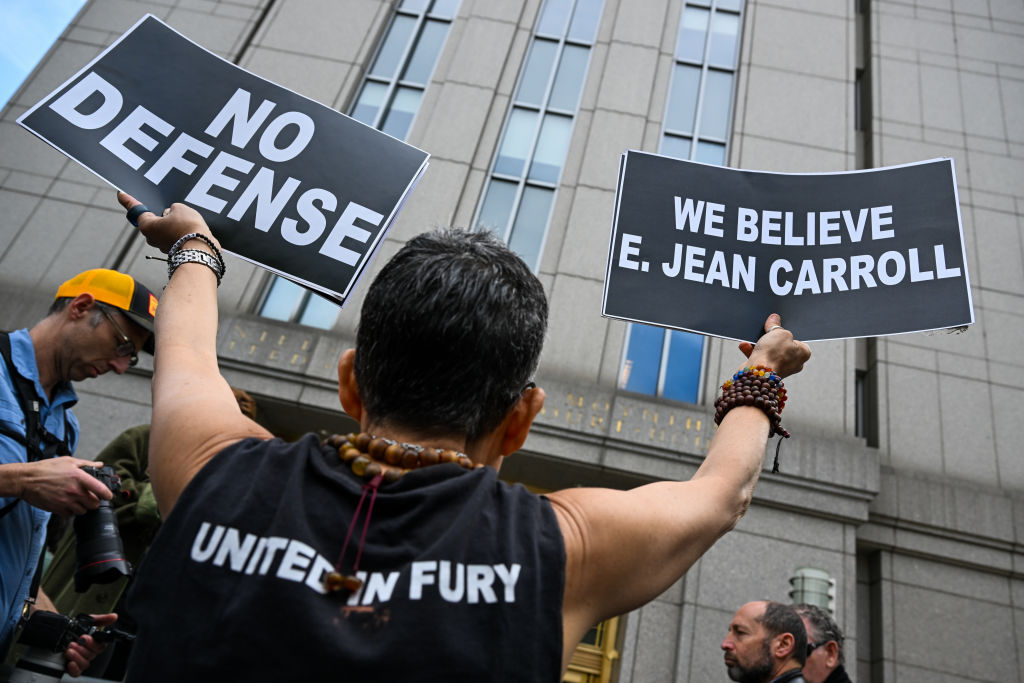 A protester holds up signs outside a Manhattan Federal Court after a jury found former President Donald Trump liable for sexually abusing E. Jean Carroll in a Manhattan department store in the 1990's on May 09, 2023 in New York City.